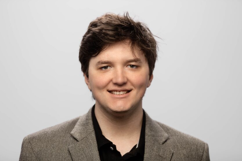 A man in a suit smiles at the camera.