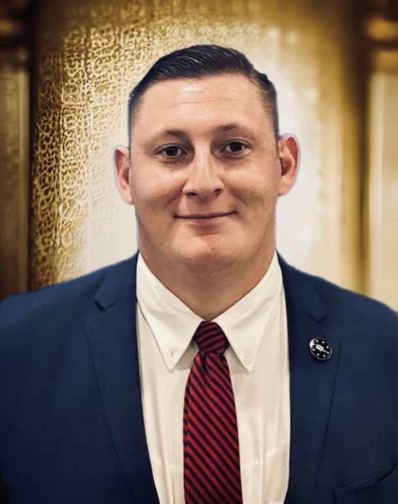 A man in a suit smiles at the camera.