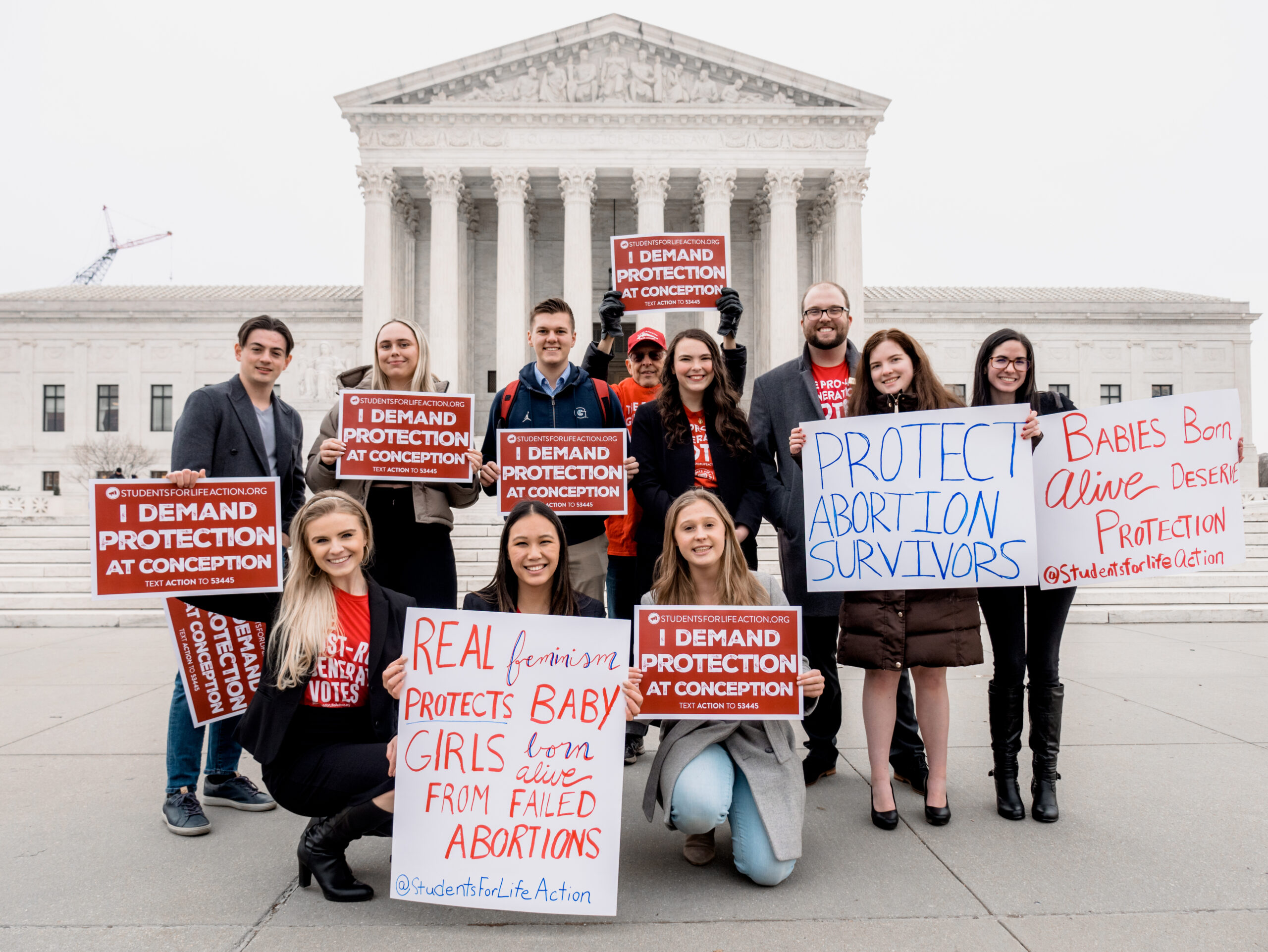 People hold signs in front of a building.