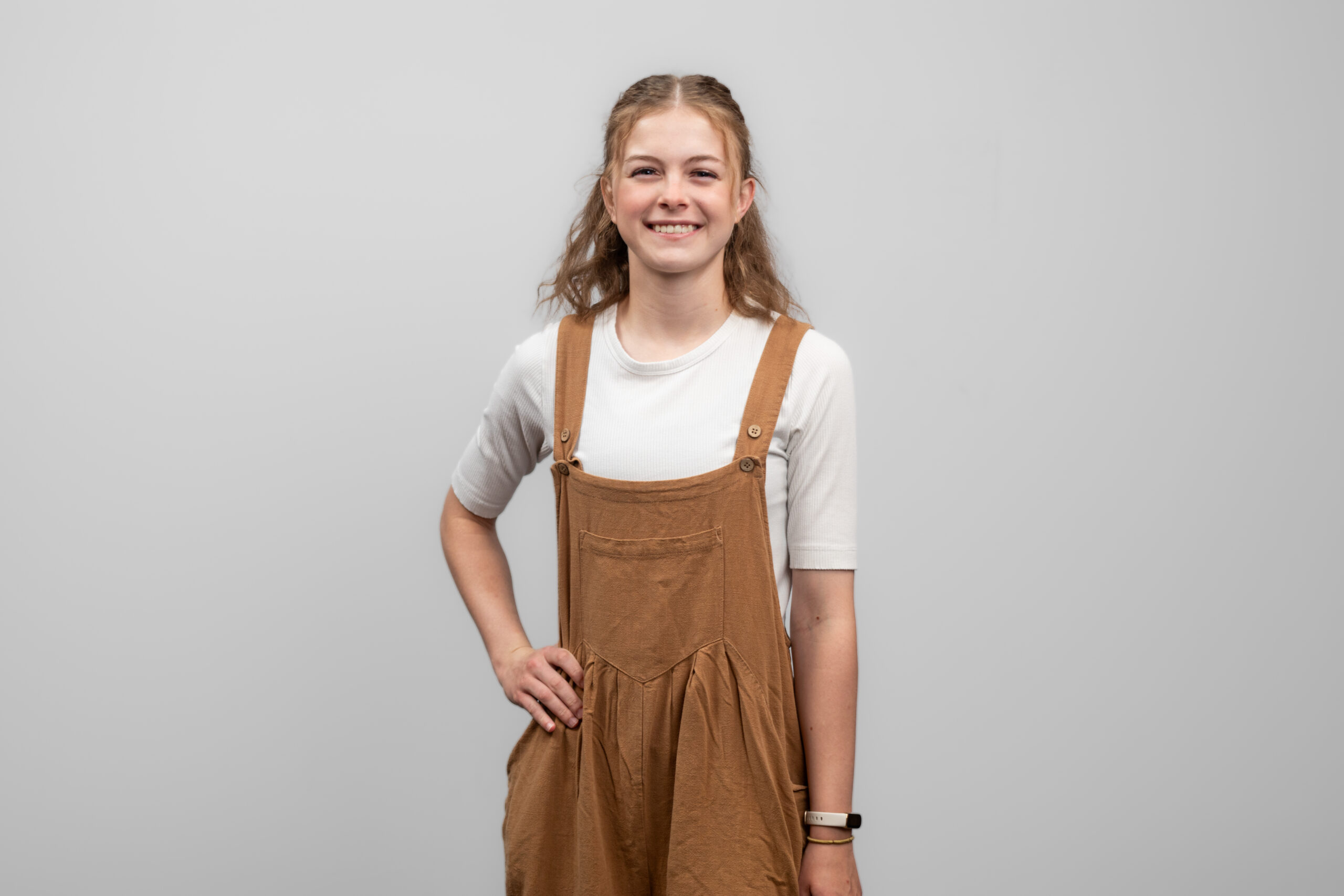 A woman stands with her hand on her hip and smiles at the camera.