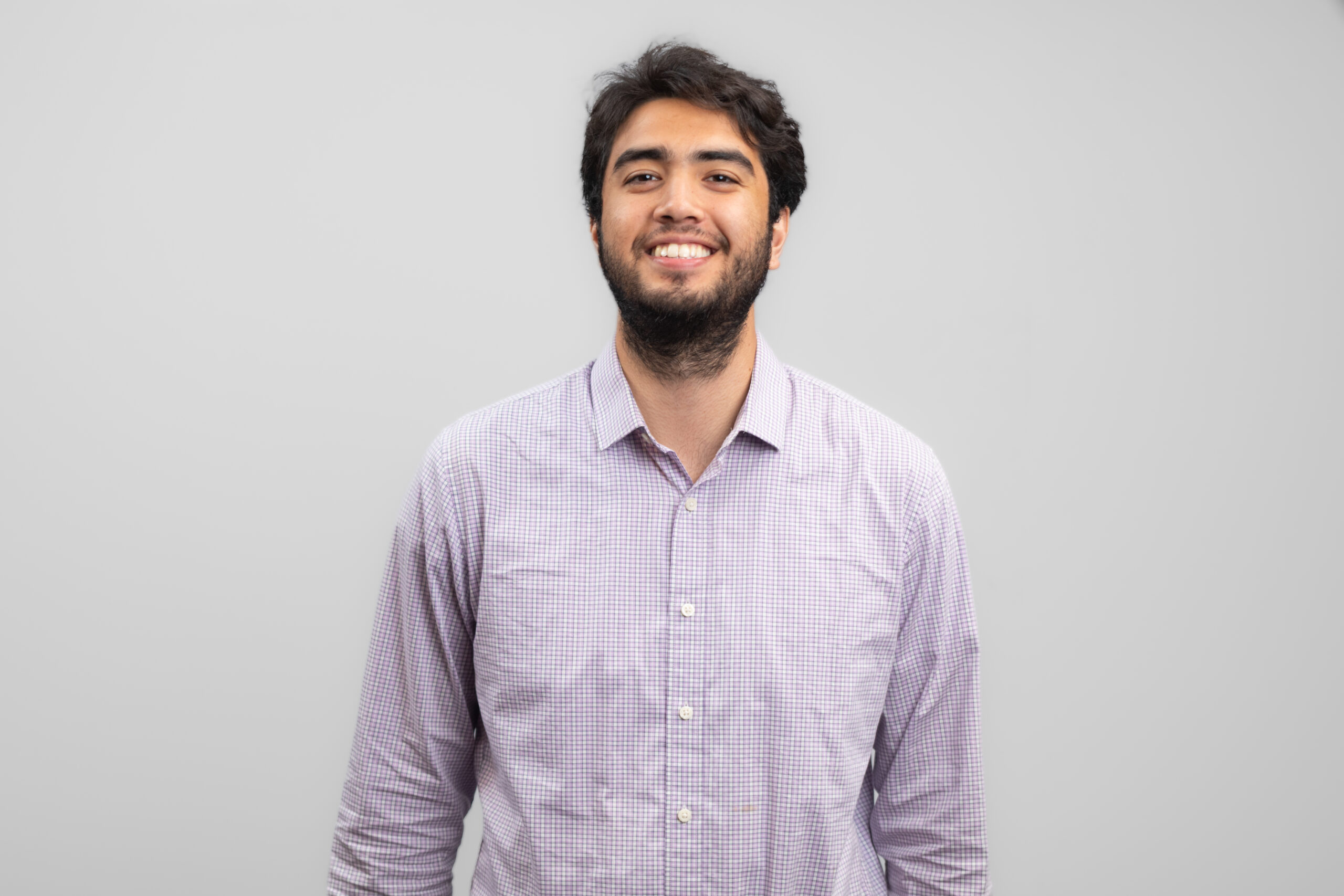 A man in a collared shirt smiles at the camera.