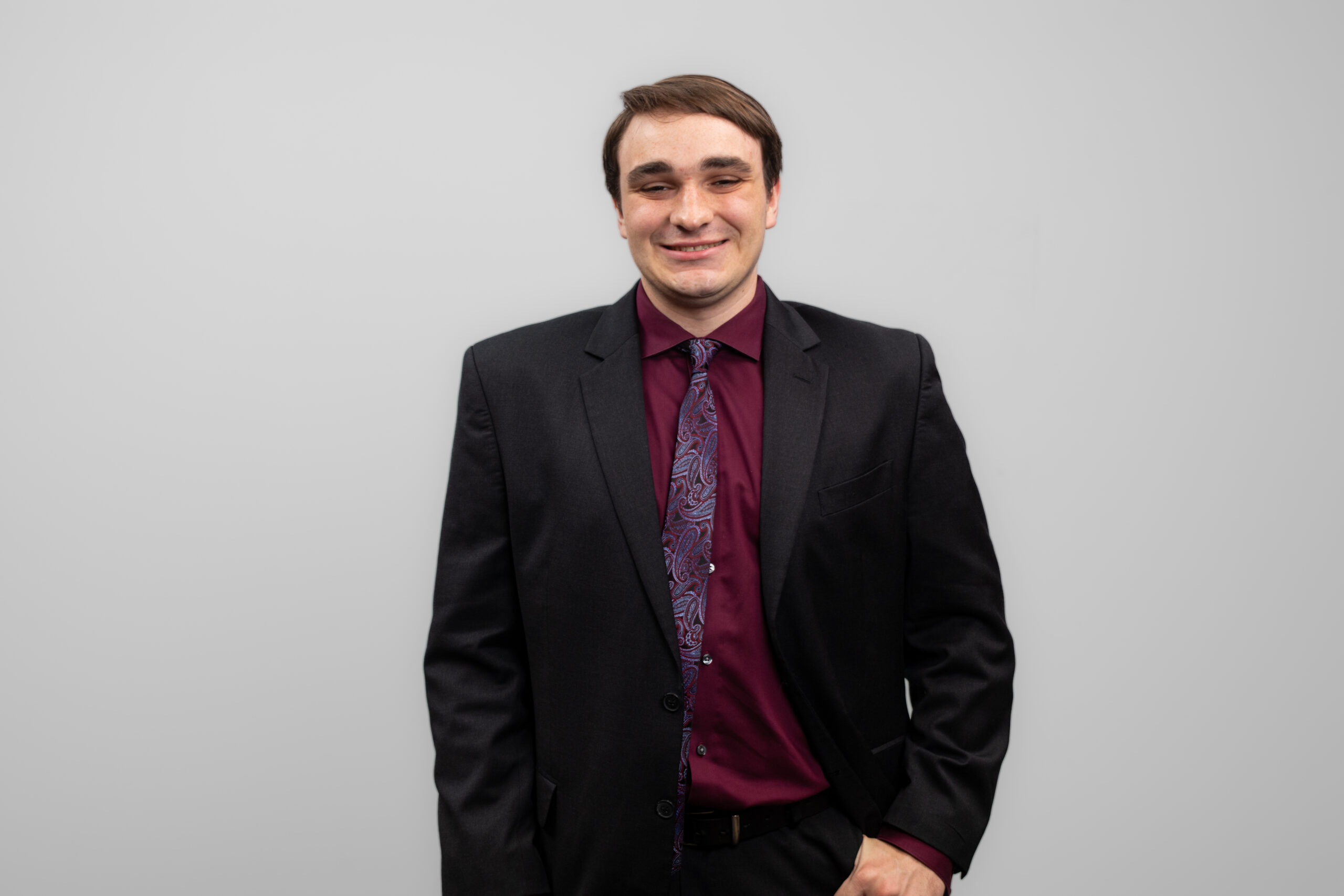 A man in a suit and tie smiles at the camera.