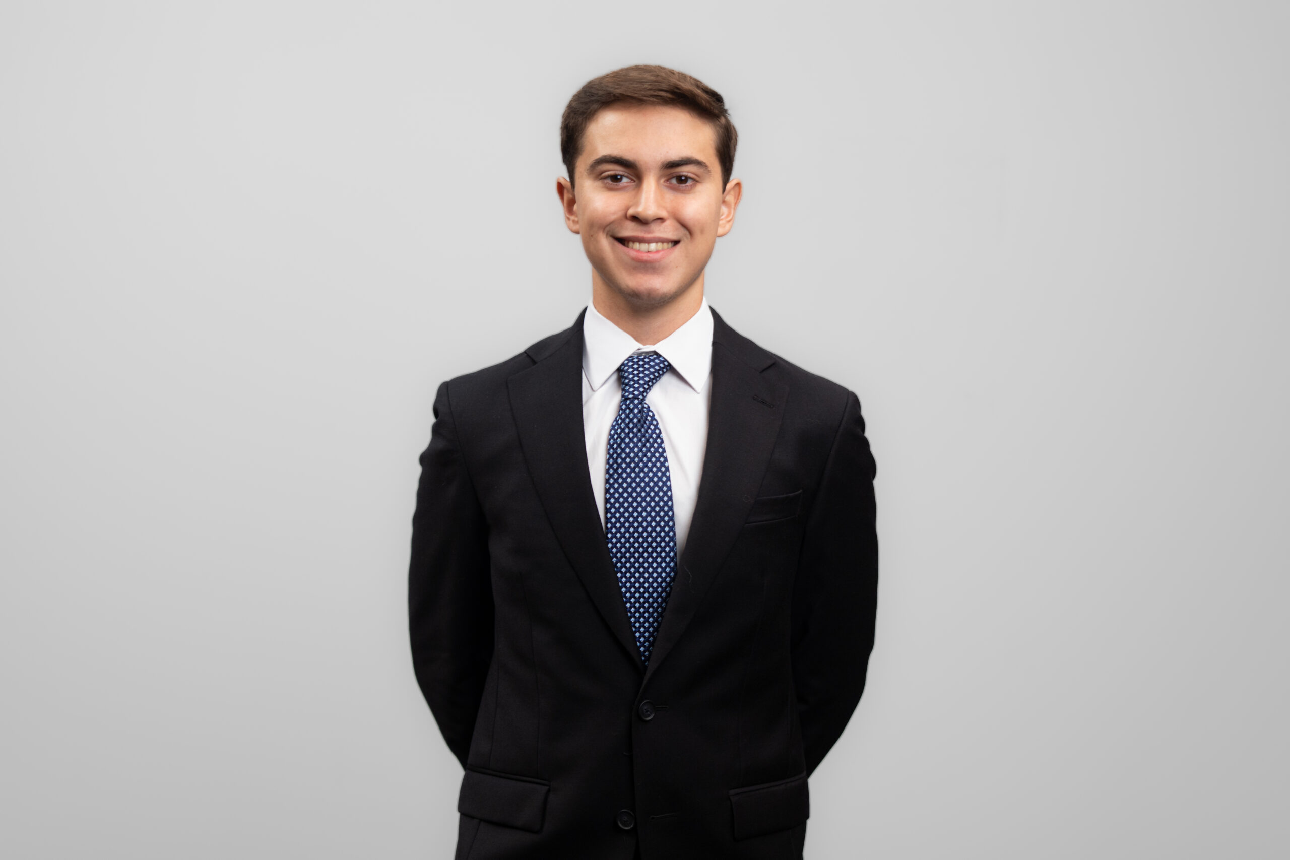 A man in a suit and tie smiles at the camera.