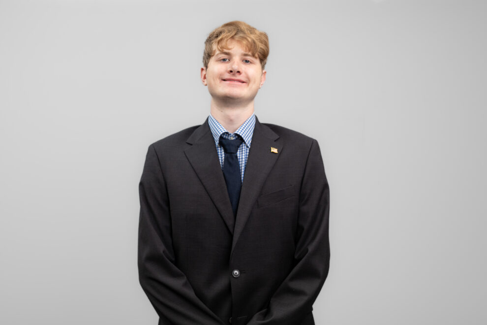 A man in a suit smiles at the camera.